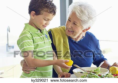 Senior woman preparing food in a kitchen with her grandson View Large Photo Image Stock Image - Senior woman preparing food in a kitchen with her grandson. Fotosearch