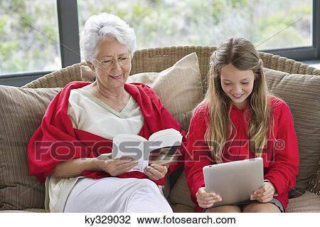 Senior woman reading a magazine with her granddaughter using a digital tablet View Large Photo Image Stock Image - Senior woman reading a magazine with her granddaughter using a digital tablet. Fotosearch