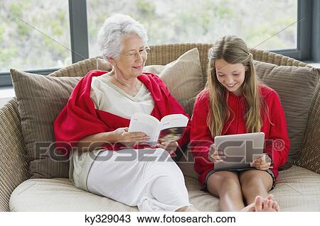 Senior woman reading a magazine with her granddaughter using a digital tablet View Large Photo Image Stock Image - Senior woman reading a magazine with her granddaughter using a digital tablet. Fotosearch