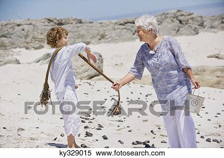 Senior woman with her grandson collecting shell on the beach View Large Photo Image Stock Photography - Senior woman with her grandson collecting shell on the beach. Fotosearch