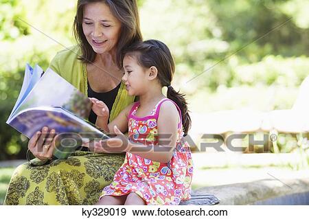 Woman with her granddaughter looking at a book View Large Photo Image Stock Photo - Woman with her granddaughter looking at a book. Fotosearch