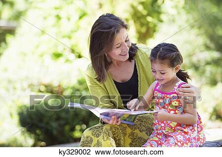 Woman with her granddaughter reading a book View Large Photo Image Stock Image - Woman with her granddaughter reading a book. Fotosearch