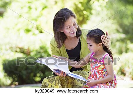 Stock Photo - Woman with her granddaughter reading a book. Fotosearch