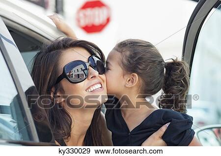 Beautiful young woman with her cute little daughter kissing in a car View Large Photo Image Stock Photo - Beautiful young woman with her cute little daughter kissing in a car. Fotosearch