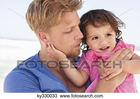 Close-up of a man carrying his daughter on the beach View Large Photo Image Stock Image - Close-up of a man carrying his daughter on the beach. Fotosearch