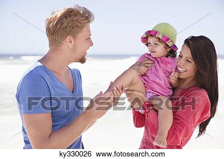 Couple enjoying on the beach with their daughter View Large Photo Image Stock Photograph - Couple enjoying on the beach with their daughter. Fotosearch