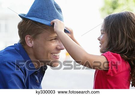 Cute little girl putting on a hat to her father View Large Photo Image Stock Image - Cute little girl putting on a hat to her father. Fotosearch