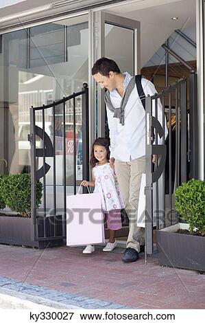 Cute little girl with her father walking out of a shopping mall with shopping bags View Large Photo Image Stock Photo - Cute little girl with her father walking out of a shopping mall with shopping bags. Fotosearch
