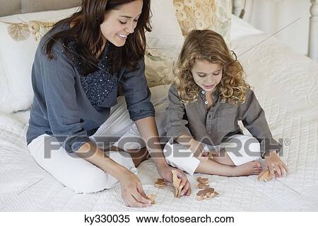 Happy mother playing with daughter in bed View Large Photo Image Stock Photography - Happy mother playing with daughter in bed. Fotosearch