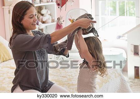 Happy woman dressing her daughter at home View Large Photo Image Stock Image - Happy woman dressing her daughter at home. Fotosearch