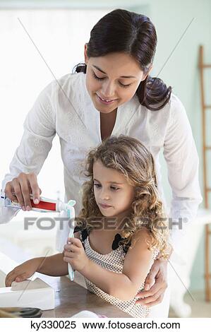 Mother applying tooth paste on little girls tooth brush at bathroom View Large Photo Image Stock Photography - Mother applying tooth paste on little girls tooth brush at bathroom. Fotosearch