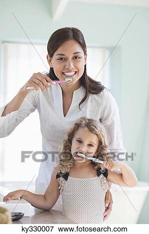 Portrait of a young woman and her daughter brushing teeth View Large Photo Image Stock Photo - Portrait of a young woman and her daughter brushing teeth. Fotosearch