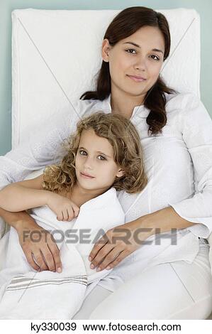 Stock Photo - Portrait of a young woman lying with her daughter wrapped in white towel. Fotosearch