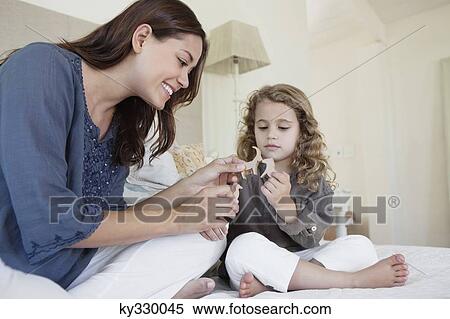 Stock Photography - Woman playing with daughter in bed. Fotosearch