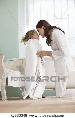 Woman rubbing noses with her daughter wrapped in towel after the bath View Large Photo Image Stock Photo - Woman rubbing noses with her daughter wrapped in towel after the bath. Fotosearch