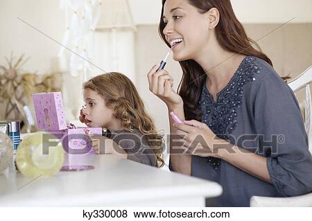 Young woman and little girl applying make-up at dressing table View Large Photo Image Stock Photo - Young woman and little girl applying make-up at dressing table. Fotosearch