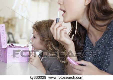 Young woman and little girl applying make-up at dressing table View Large Photo Image Stock Photo - Young woman and little girl applying make-up at dressing table. Fotosearch