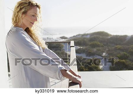 Mid adult woman standing at a balcony View Large Photo Image Stock Photo - Mid adult woman standing at a balcony. Fotosearch