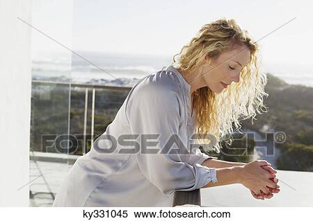Mid adult woman standing at a balcony View Large Photo Image Stock Photography - Mid adult woman standing at a balcony. Fotosearch