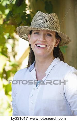 Stock Photo - Portrait of a beautiful mature woman wearing hat and smiling. Fotosearch