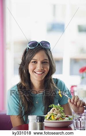 Stock Photo - Portrait of a beautiful woman eating food in a restaurant. Fotosearch