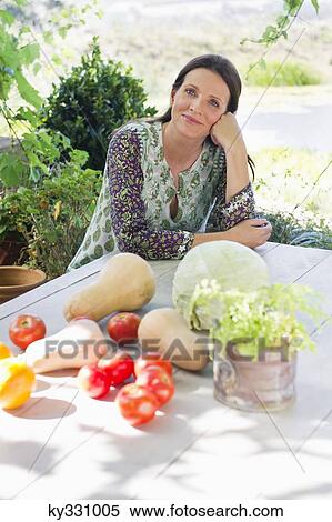 Portrait of a mature woman sitting and vegetables on table View Large Photo Image Stock Photography - Portrait of a mature woman sitting and vegetables on table. Fotosearch