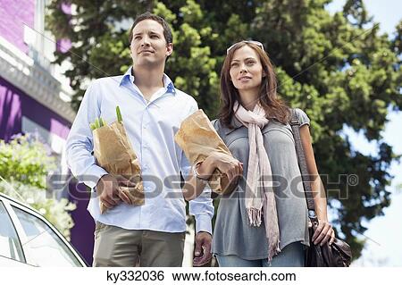 Couple standing with paper bags full of vegetables View Large Photo Image Stock Photograph - Couple standing with paper bags full of vegetables. Fotosearch