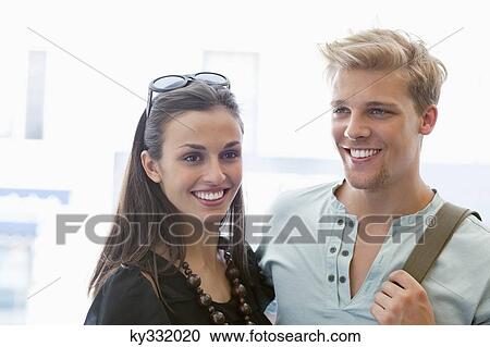Smiling young couple standing together View Large Photo Image Stock Image - Smiling young couple standing together. Fotosearch
