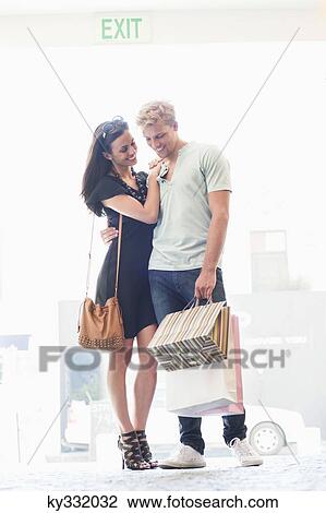 Smiling young couple standing with shopping bags View Large Photo Image Stock Image - Smiling young couple standing with shopping bags. Fotosearch