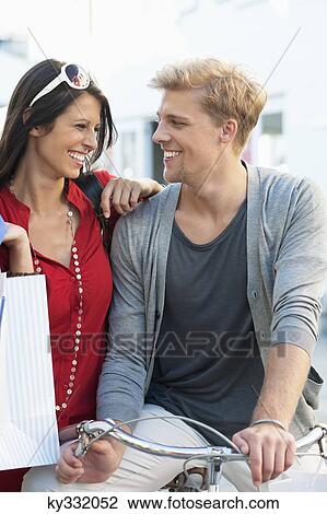 Young couple looking at each other on a bicycle View Large Photo Image Stock Image - Young couple looking at each other on a bicycle. Fotosearch