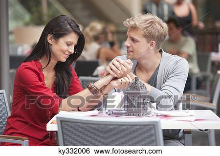 Young man holding hands of his girlfriend in a restaurant View Large Photo Image Stock Photograph - Young man holding hands of his girlfriend in a restaurant. Fotosearch