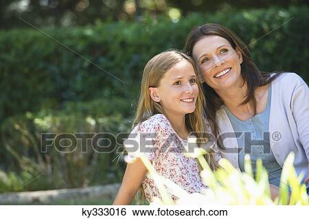 Stock Photograph - Cute little girl and her mother sitting together in the garden. Fotosearch