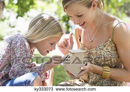 Little girl and her mother looking at dollhouse outdoors View Large Photo Image Stock Image - Little girl and her mother looking at dollhouse outdoors. Fotosearch