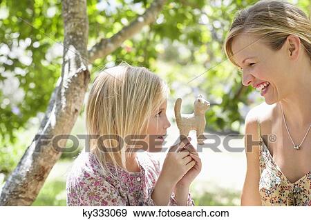 Stock Photo - Little girl and her mother looking at toy in hand outdoors. Fotosearch