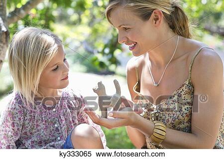 Little girl and her mother looking at toy in hand outdoors View Large Photo Image Stock Photography - Little girl and her mother looking at toy in hand outdoors. Fotosearch