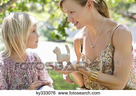 Little girl and her mother with a toy in hand outdoors View Large Photo Image Stock Photograph - Little girl and her mother with a toy in hand outdoors. Fotosearch