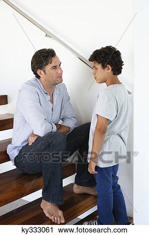 Stock Image - Mid adult man talking to his son. Fotosearch