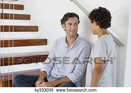 Stock Photography - Mid adult man talking to his son. Fotosearch
