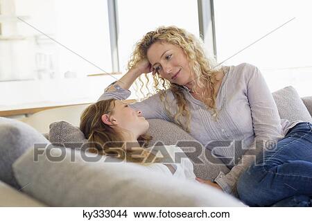 Mid adult woman and her daughter looking at each other on a couch View Large Photo Image Picture - Mid adult woman and her daughter looking at each other on a couch. Fotosearch