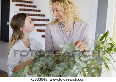 Mid adult woman and her daughter touching leaves and smiling View Large Photo Image Stock Photo - Mid adult woman and her daughter touching leaves and smiling. Fotosearch