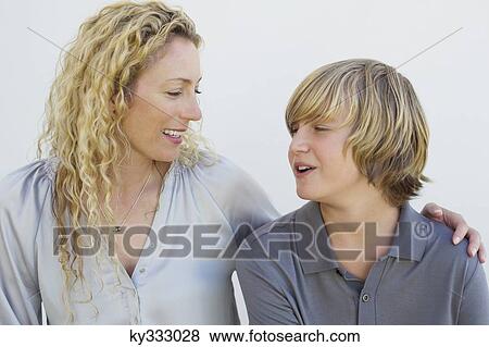 Mid adult woman and her son looking at each other and smiling View Large Photo Image Stock Photo - Mid adult woman and her son looking at each other and smiling. Fotosearch