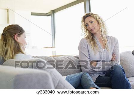 Mid adult woman looking at her daughter sitting on a couch View Large Photo Image Stock Image - Mid adult woman looking at her daughter sitting on a couch. Fotosearch