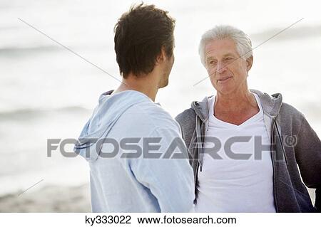 Senior man talking to his son on the beach View Large Photo Image Stock Image - Senior man talking to his son on the beach. Fotosearch