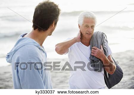 Senior man talking to his son on the beach View Large Photo Image Stock Photo - Senior man talking to his son on the beach. Fotosearch