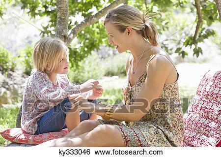 Stock Photograph - Side profile of mother and a little girl looking to each other outdoors. Fotosearch