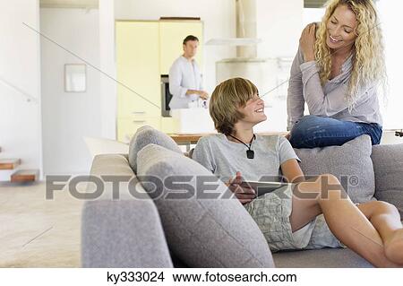Teenage boy using a digital tablet and talking to his mother View Large Photo Image Picture - Teenage boy using a digital tablet and talking to his mother. Fotosearch