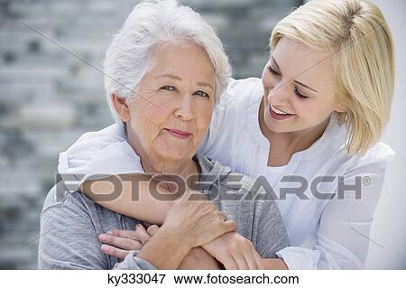 Stock Photo - Young woman embracing her mother from behind. Fotosearch