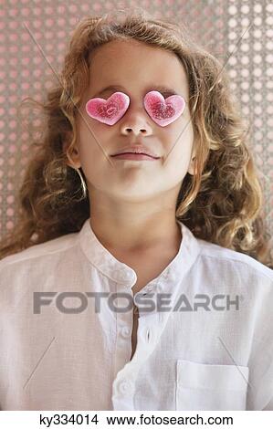 Close-up of a cute little girl covering her eyes with heart shape toys View Large Photo Image Picture - Close-up of a cute little girl covering her eyes with heart shape toys. Fotosearch