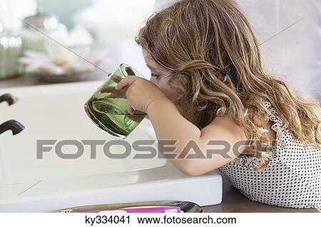 Cute little girl drinking water at bathroom sink View Large Photo Image Stock Image - Cute little girl drinking water at bathroom sink. Fotosearch