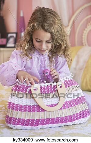 Stock Photo - Cute little girl looking into a bag on the bed. Fotosearch